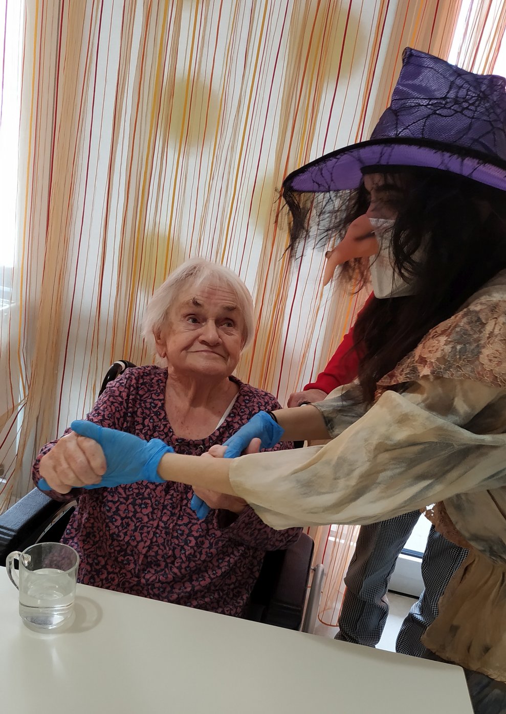 Eine verkleidete Betreuerin hält die Hände einer Bewohnerin.