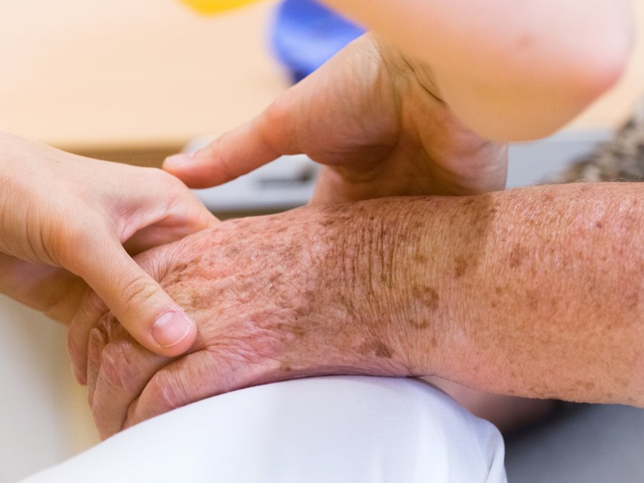 Eine Betreuerin streicht über die Hand eines Bewohners.