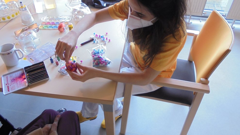 Eine Betreuerin dekoriert Ostereier.