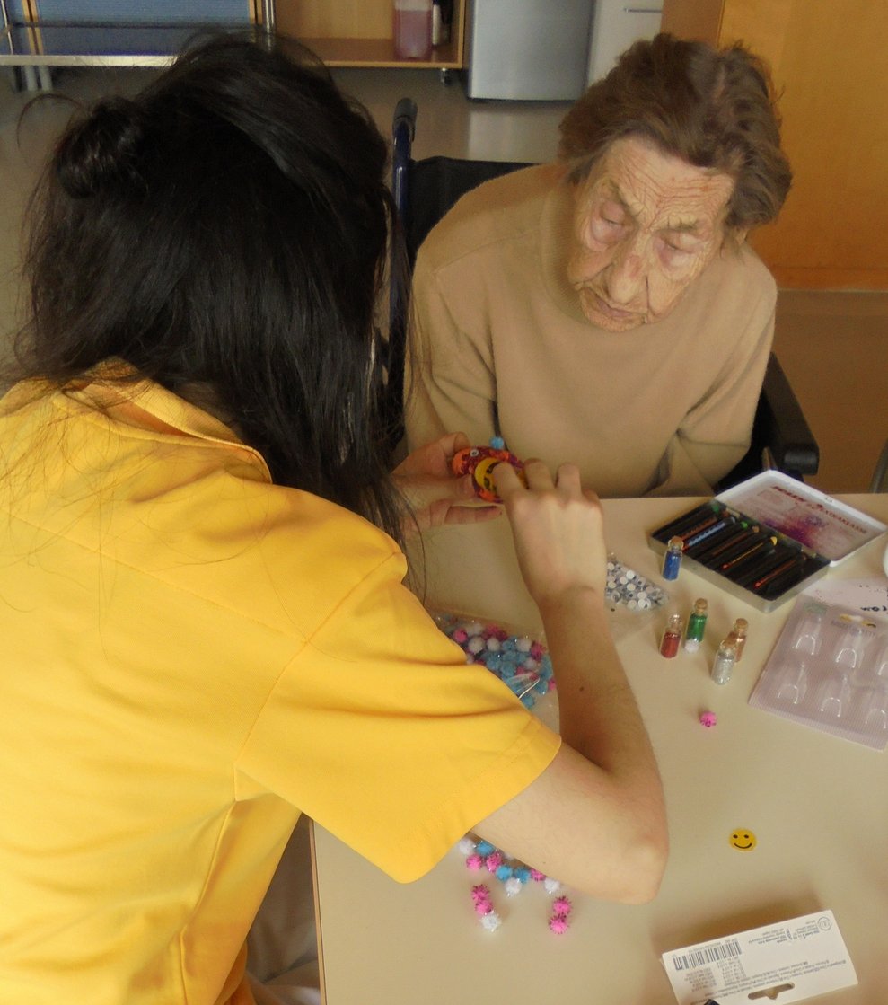 Eine Bewohnerin und eine Betreuerin dekorieren Ostereier.