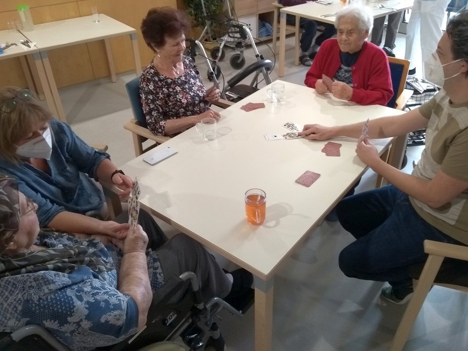Bewohnerinnen und ein Betreuer spielen Karten.